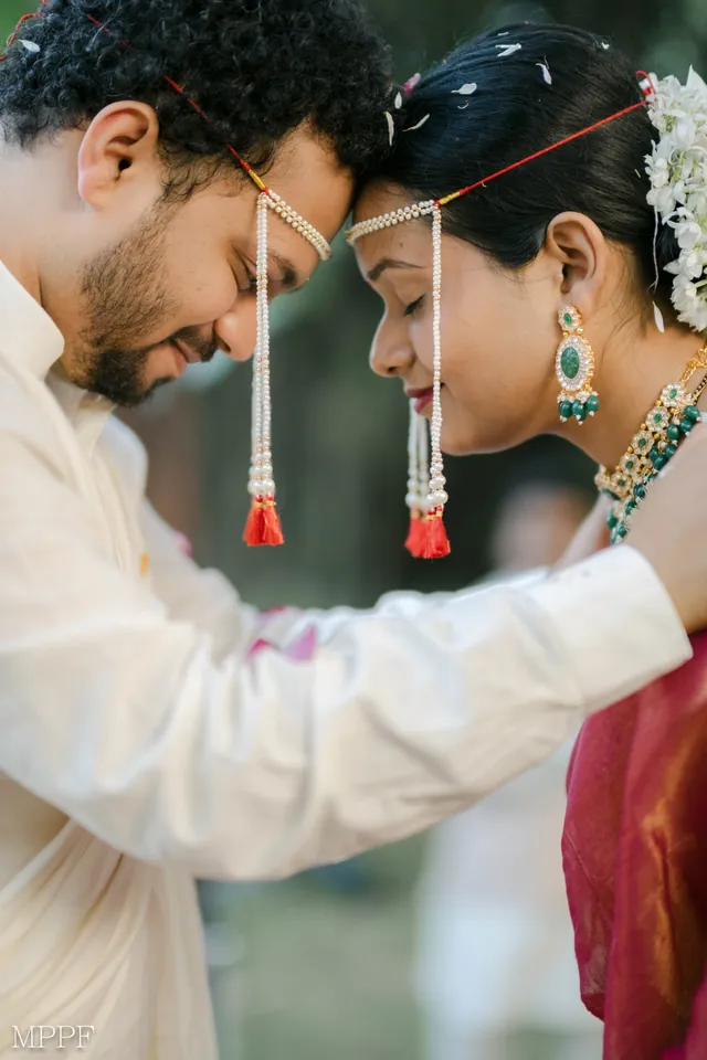 Bride and groom in pearl mundavalya, foreheads together