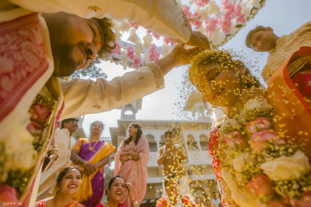 A low-angle view as the groom showers rice over the bride while family members laugh around them